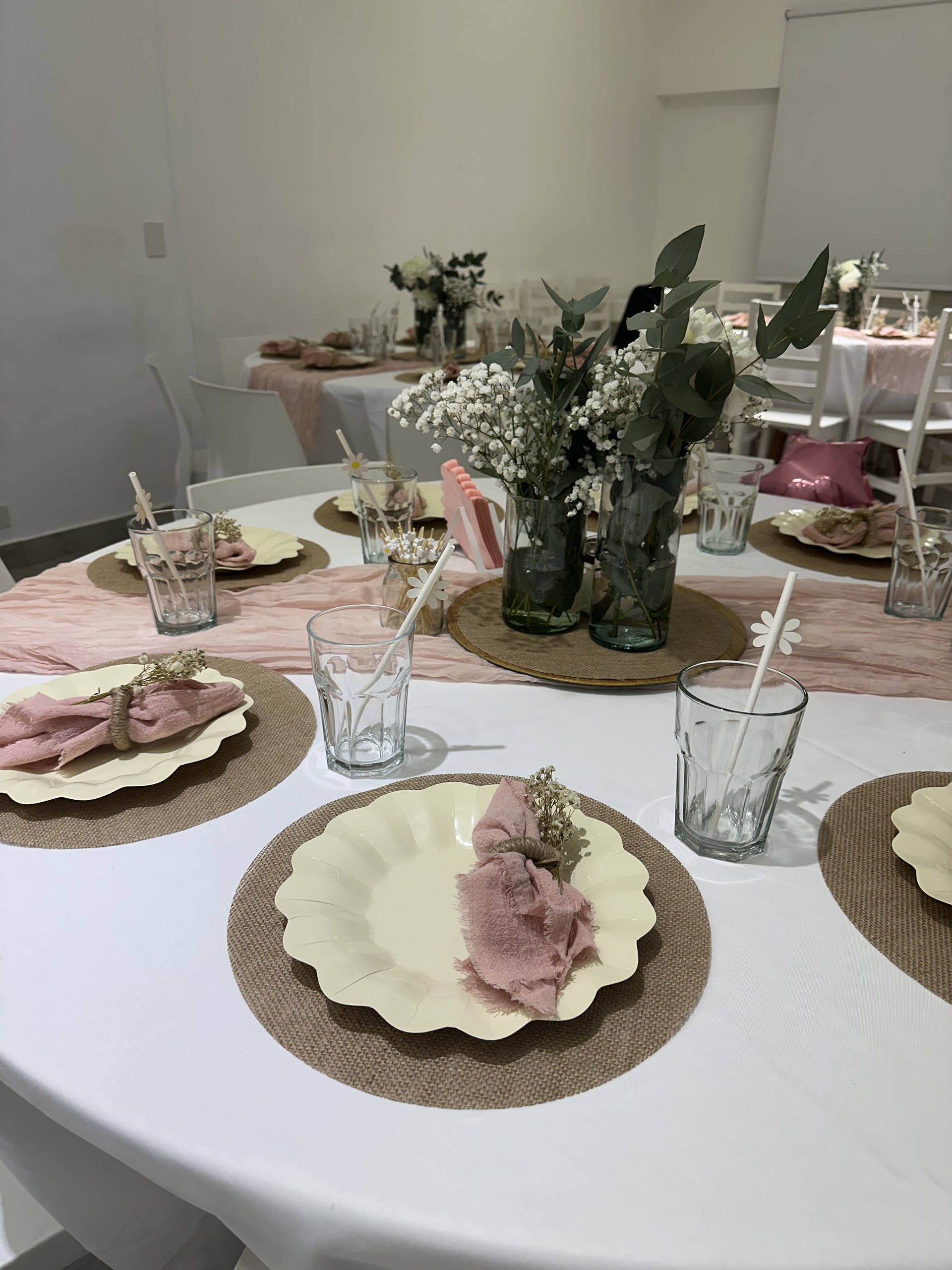 Mesa servida con vajilla, flores y detalles en tonos rosados en el salón